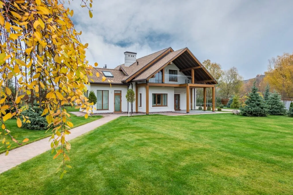 pexels-photo-5997996 Exterior of residential suburban cottage with balcony surrounded with lush green plants and trees